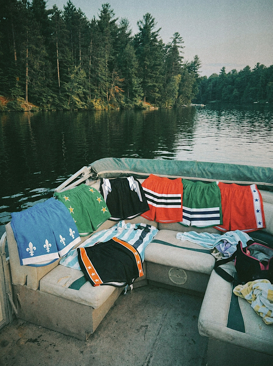 Showcasing our Beach Breezers (swim trunks) across the back of the boat on a lake. 