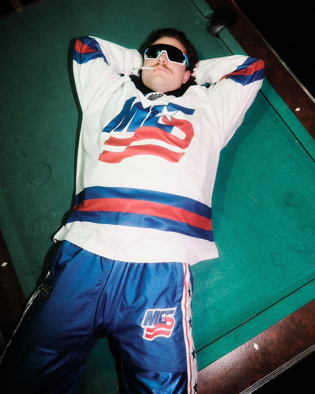 Custom hockey jersey guy relaxing on a pool table