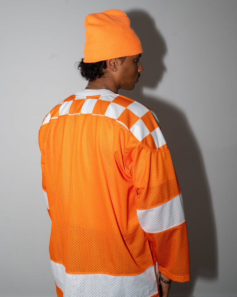 Person wearing an orange safety jacket and hat against a gray background