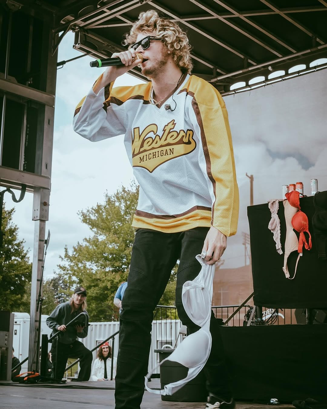 Person on stage wearing a 'Western Michigan' jacket, holding a microphone.