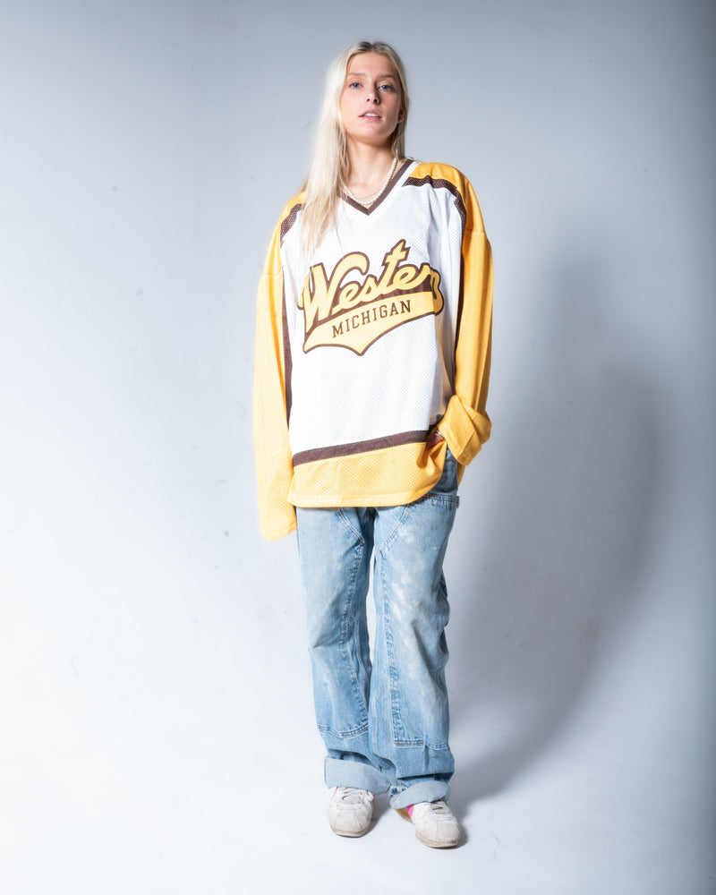 Woman wearing a white retro hockey jersey with text, standing against a plain background