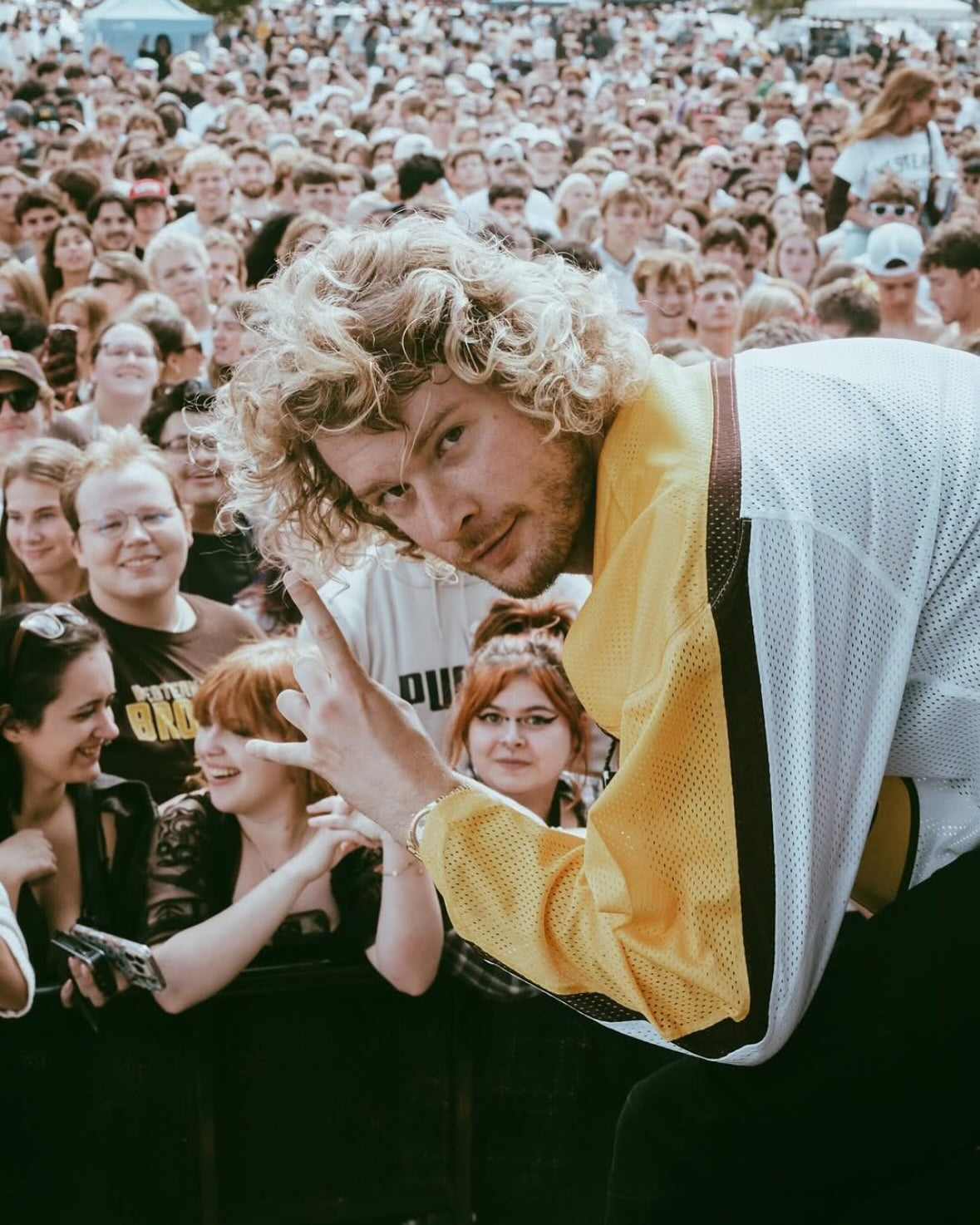Yung Gravy poses in front of the concert crowd while on stage in Kalamazoo wearing a white Western Michigan hockey jersey